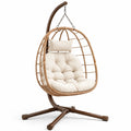 Poltrona sospesa in rattan con cuscini crema e struttura in metallo